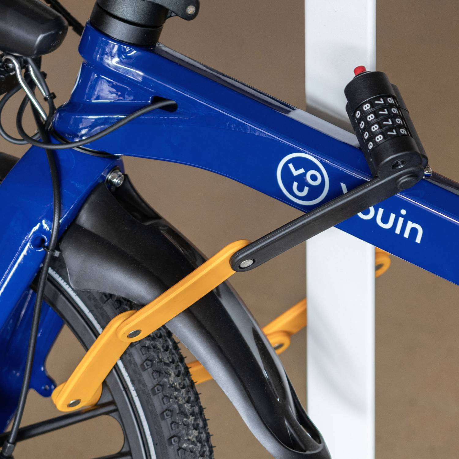 Una bicicleta azul con candado de combinación, candado plegable amarillo y guardabarros negro.