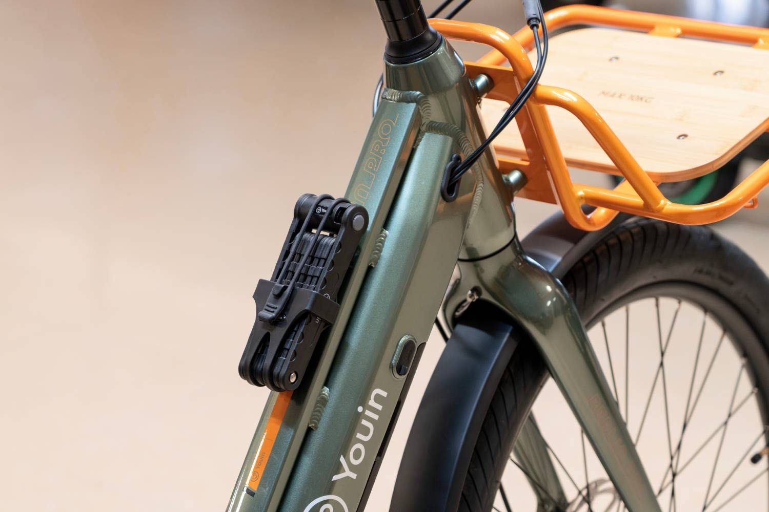 Bicicleta verde con portabultos naranja y candado negro en el cuadro.