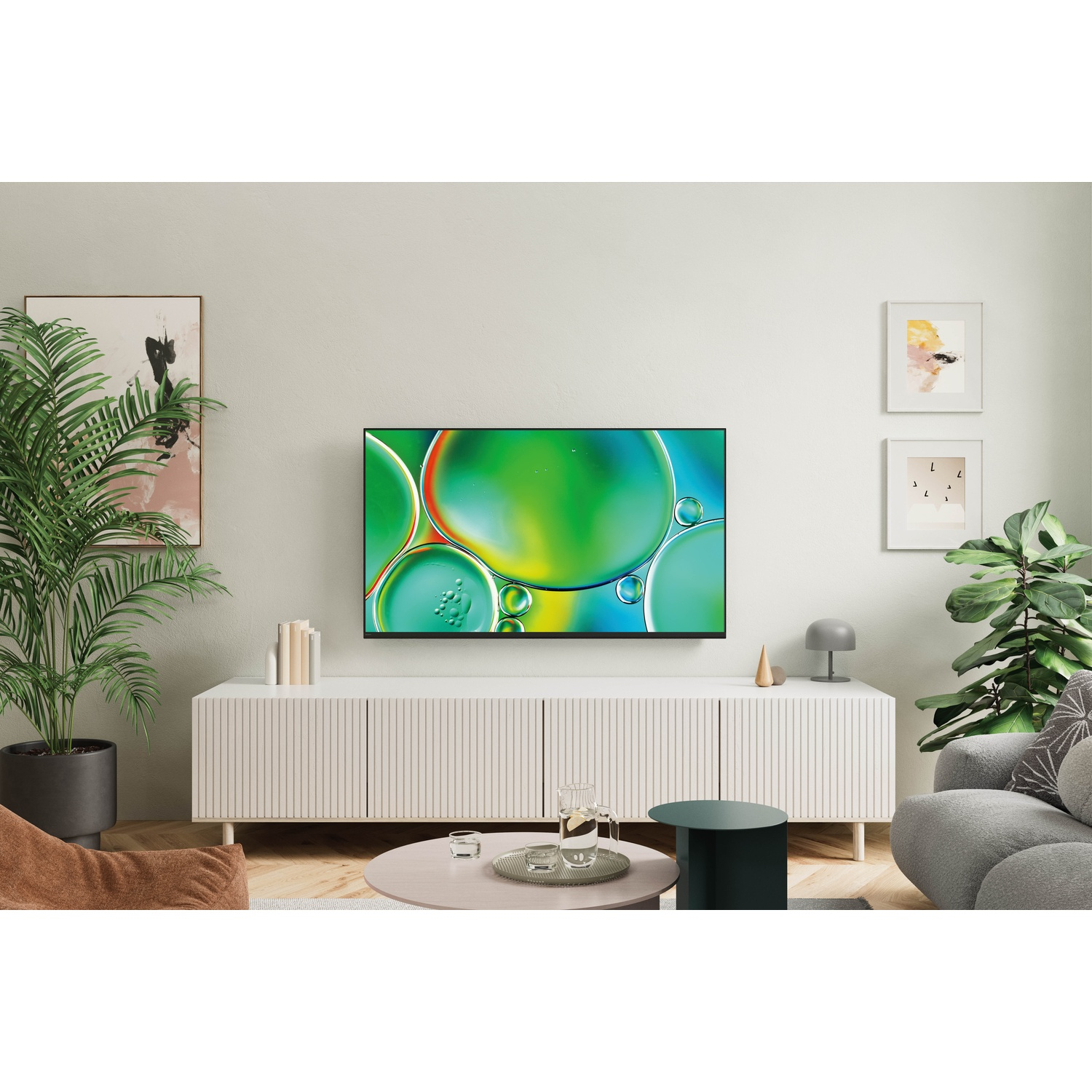 Moderne woonkamer met grote tv die abstracte kunst, planten en meubels toont.