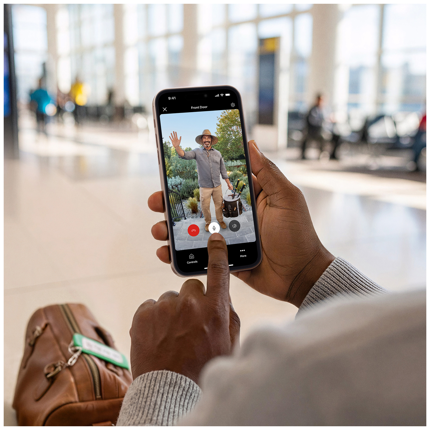 Man waves on phone video call, airport in background.