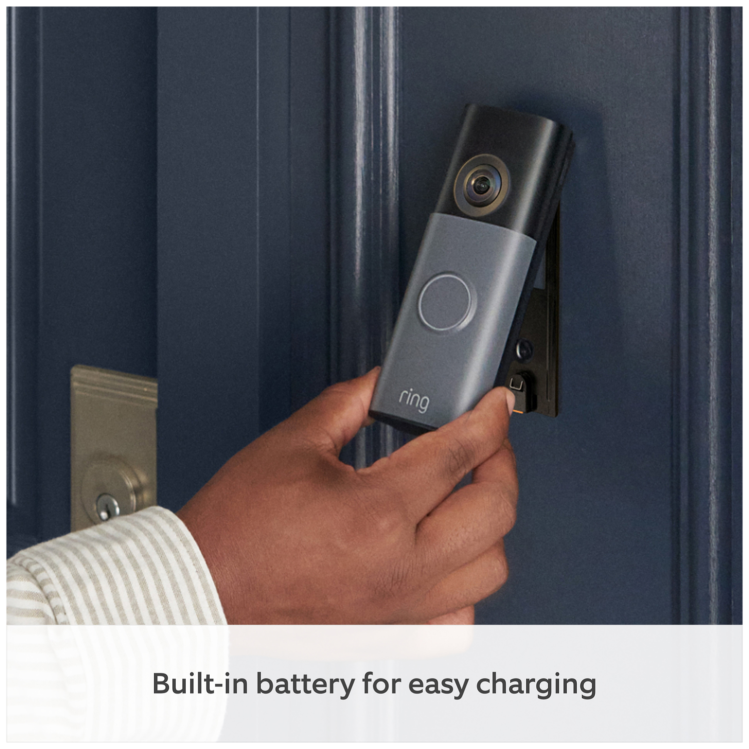 A hand mounts a gray doorbell camera onto a blue door.