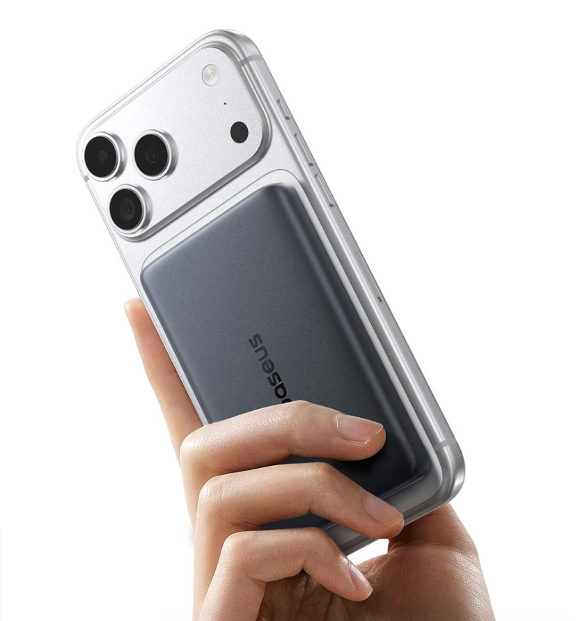 Bir el, arkasında koyu renkli bir powerbank bulunan gümüş bir akıllı telefon tutuyor.