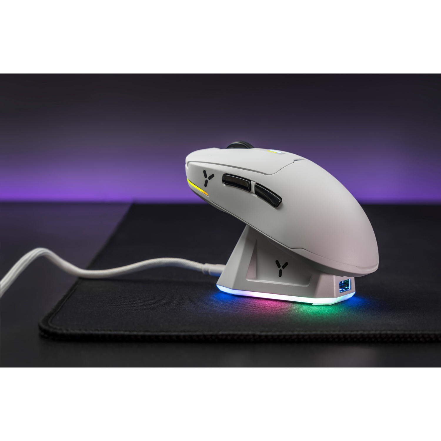 Mouse wireless bianco su dock di ricarica con luci RGB, su tappetino nero.