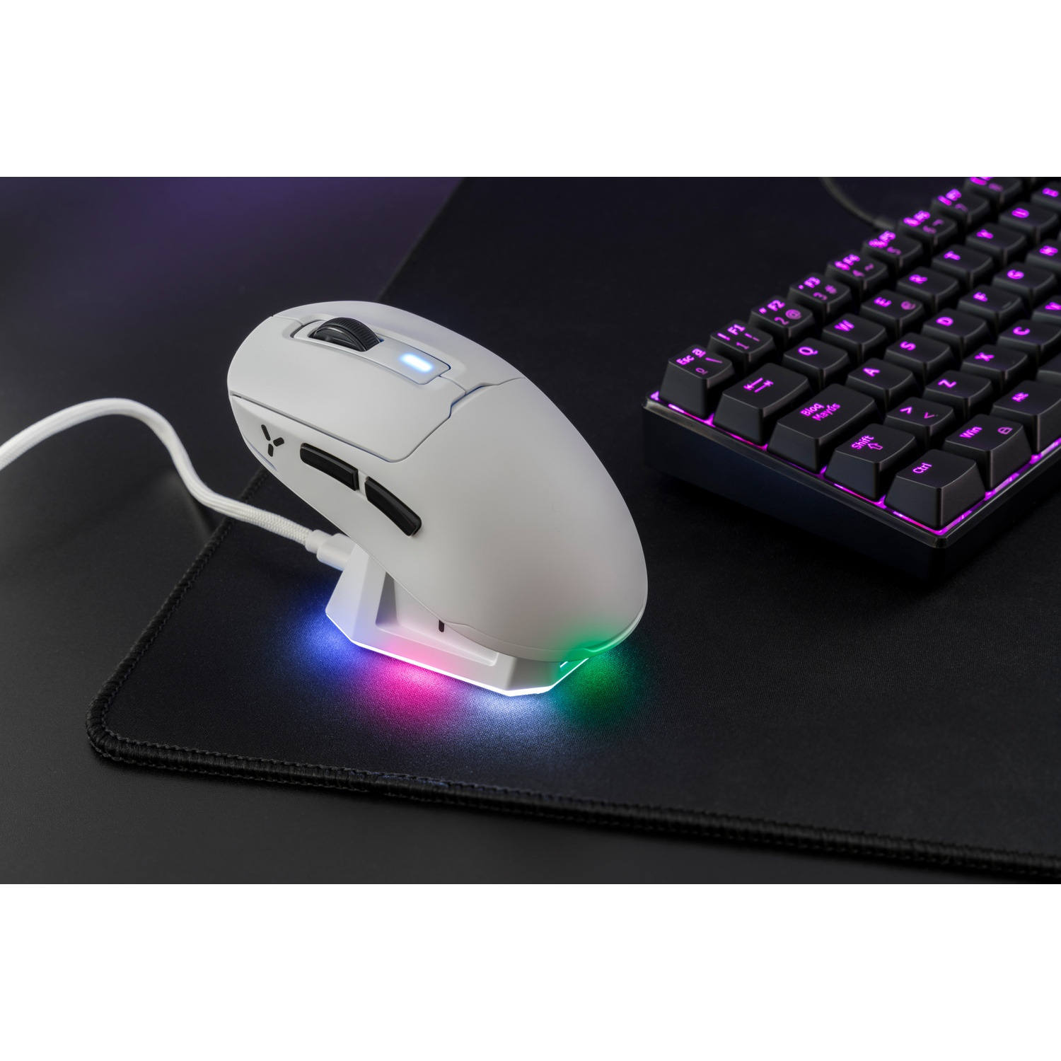 Un mouse da gaming bianco riposa su un tappetino nero, con una tastiera illuminata di rosa nelle vicinanze.