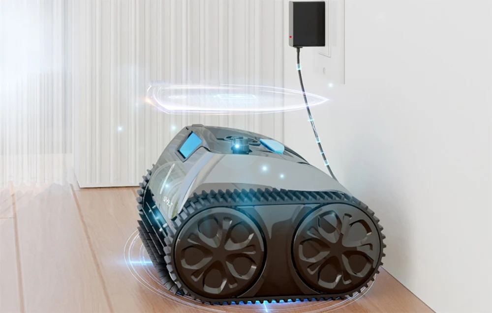Egy fekete, lánctalpas robot töltődik egy fali aljzatról.