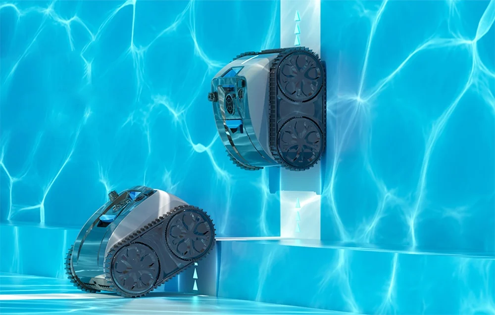 Két lánctalpas robot medencetisztító mászik fel egy világoskék medencefalon.