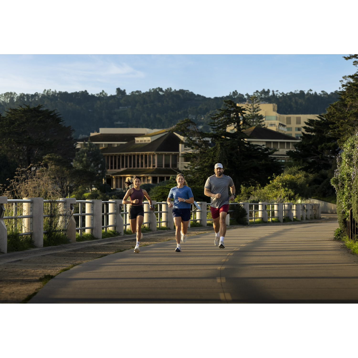 Three runners on a path with trees and buildings in the background.