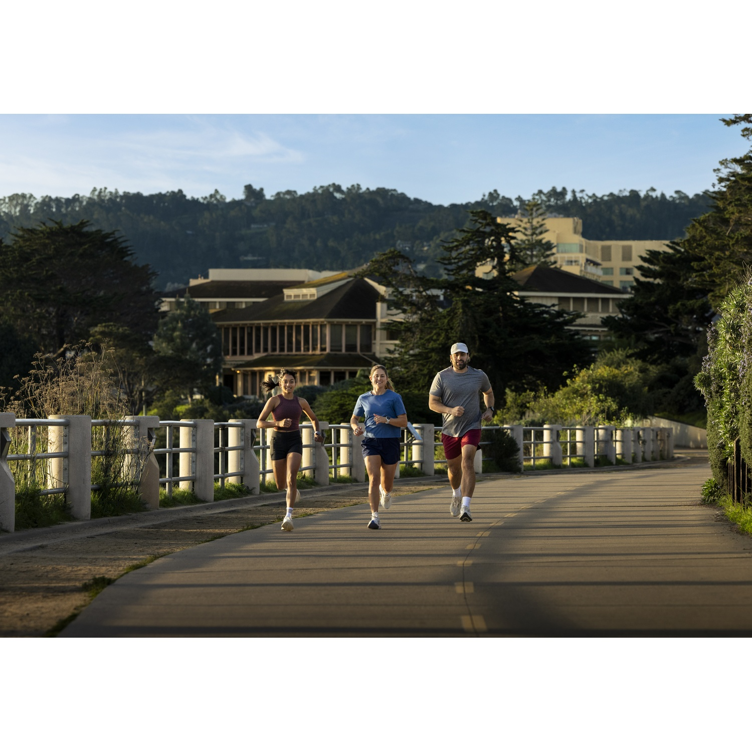 Three runners on a path with trees and buildings in the background.