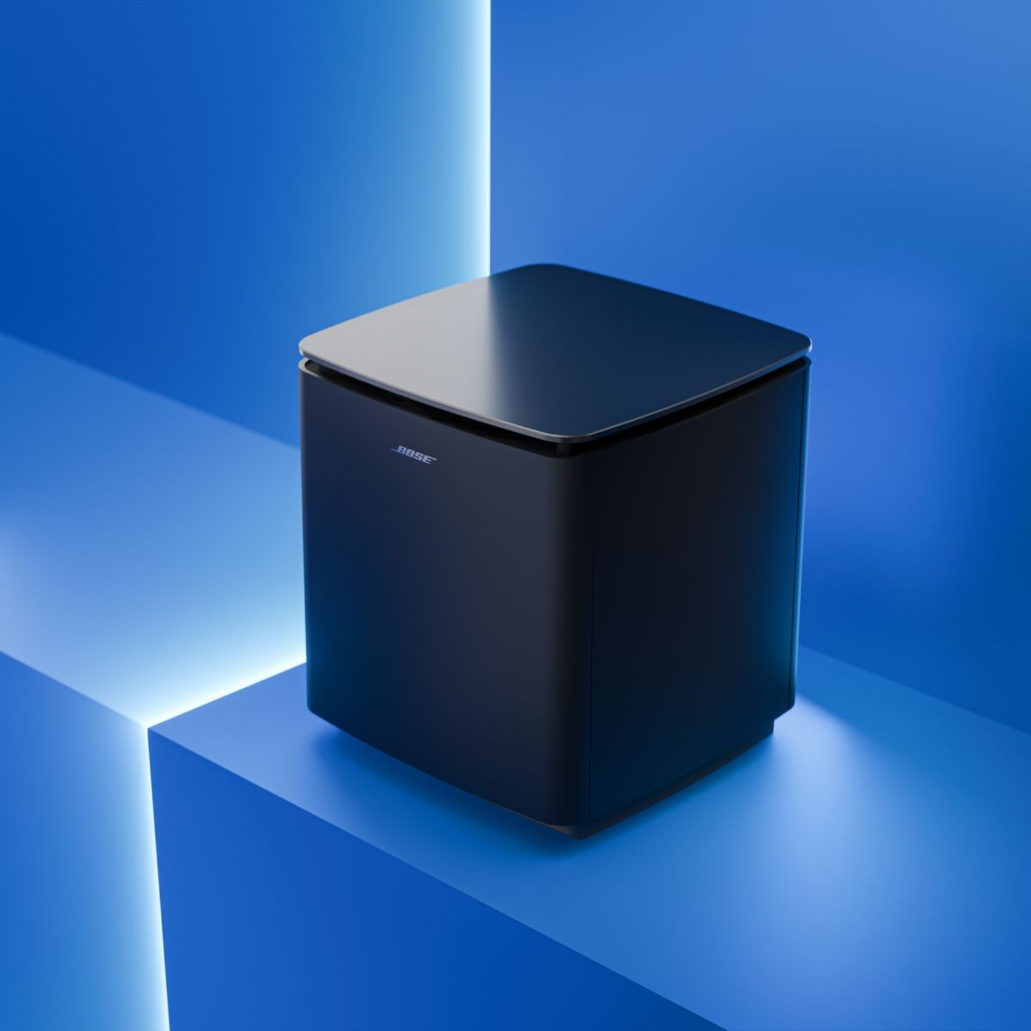 A black Bose subwoofer sits on blue cubes with glowing edges.