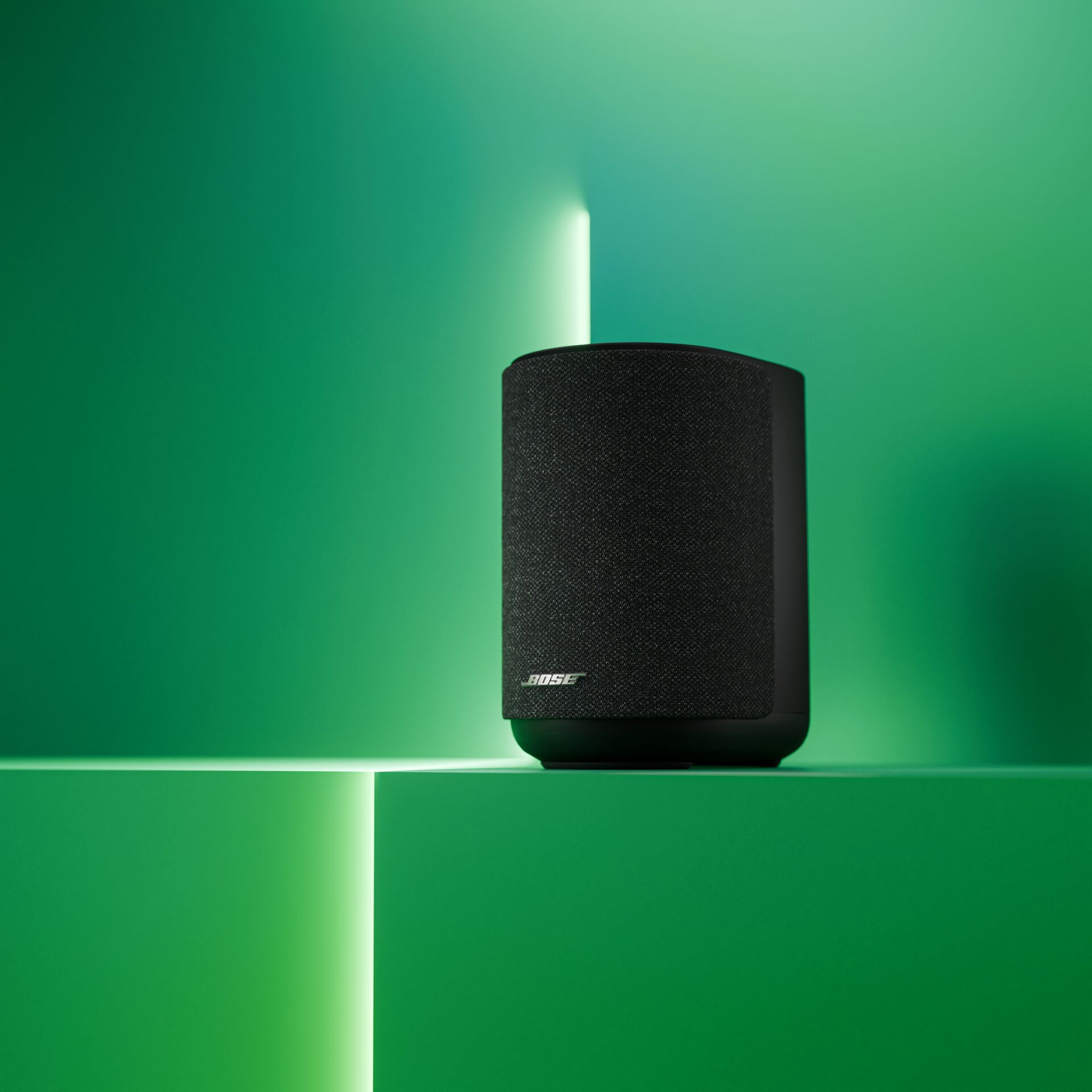 Black Bose speaker on a green platform with a light effect.