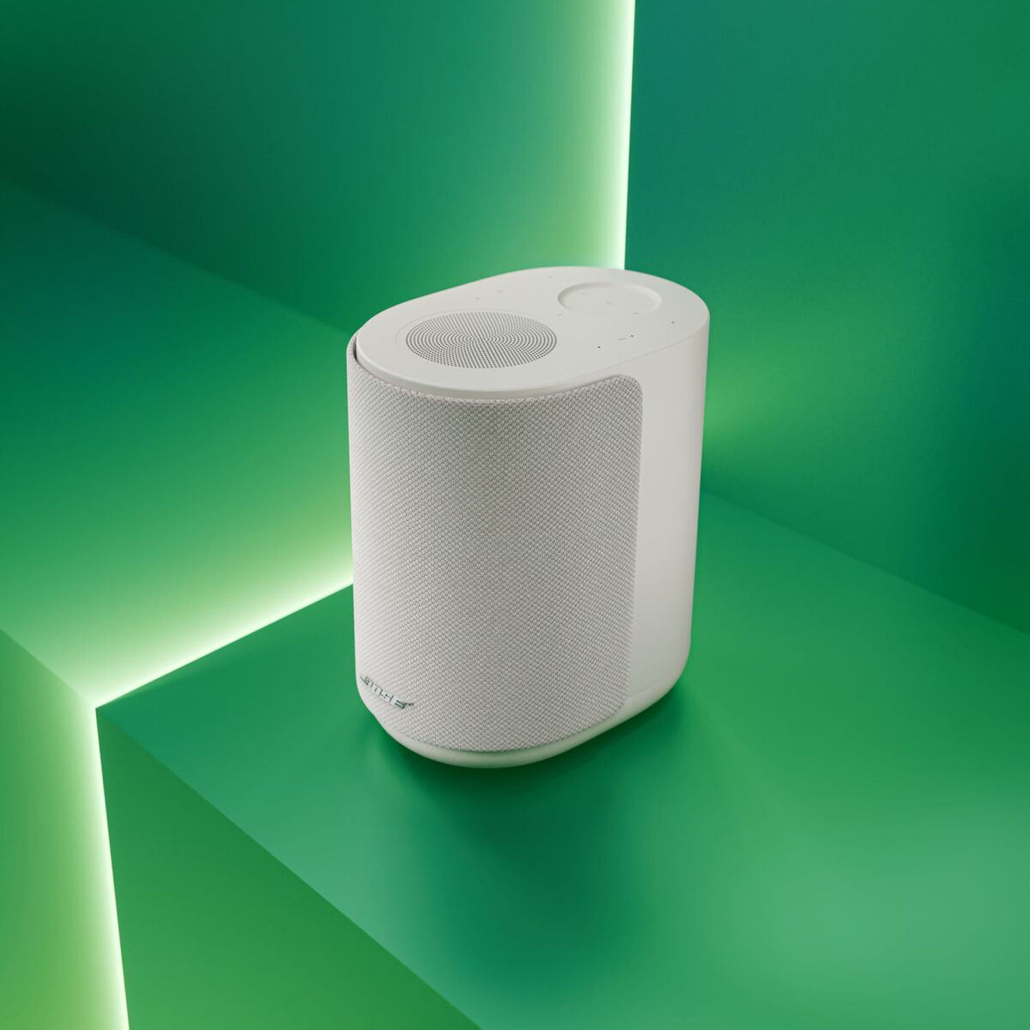 Een witte Bose luidspreker rust op een groen, geometrisch oppervlak.