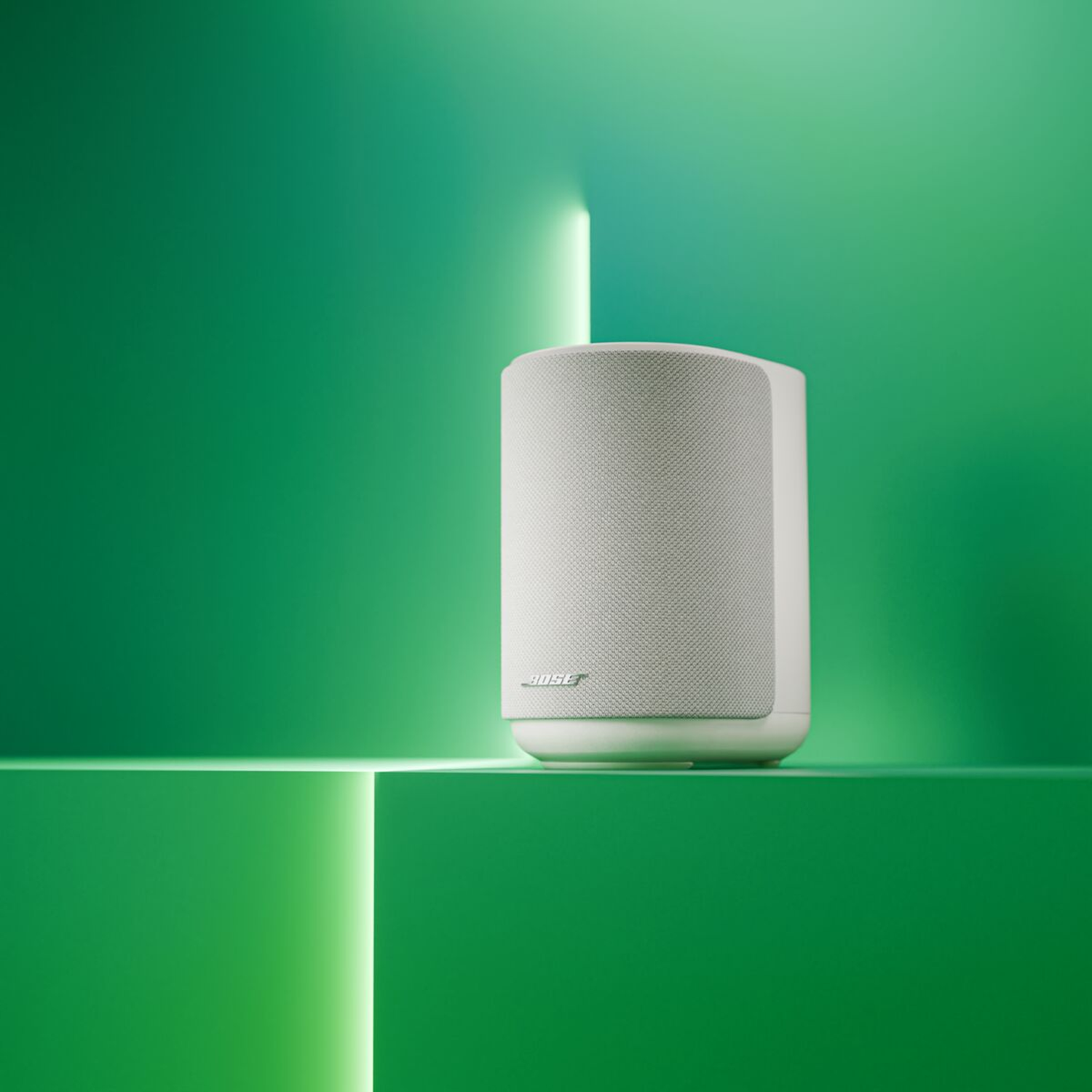 Een witte Bose speaker staat op een groen oppervlak met neonverlichting.