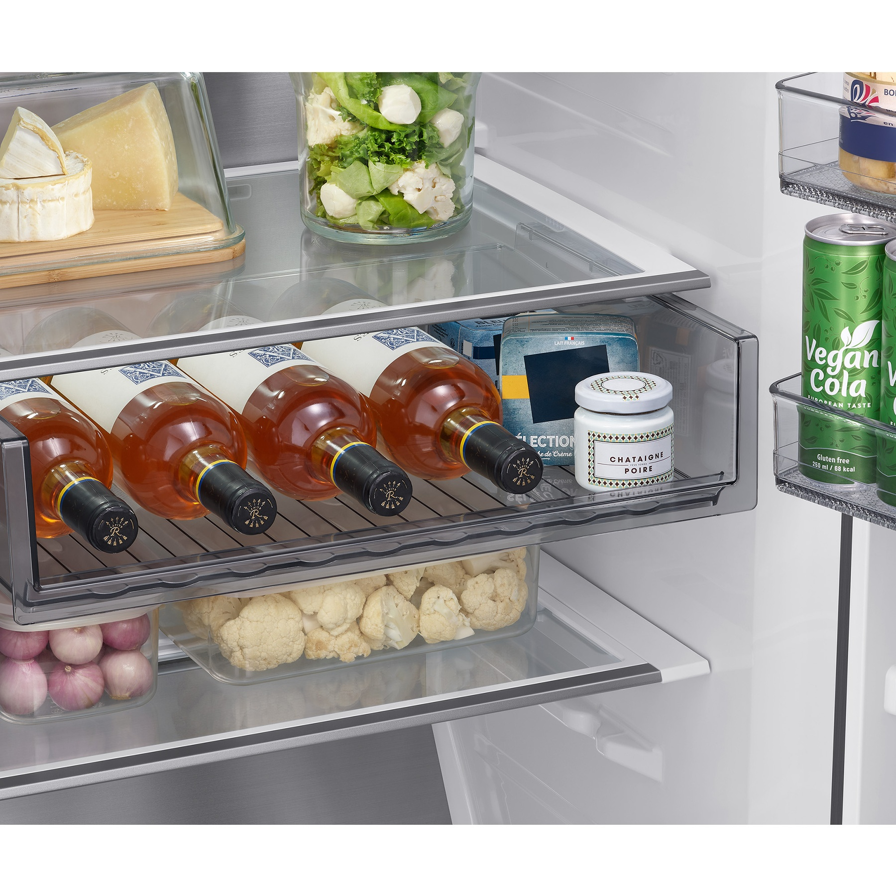 Estante de refrigerador con botellas, queso, ensalada y latas.