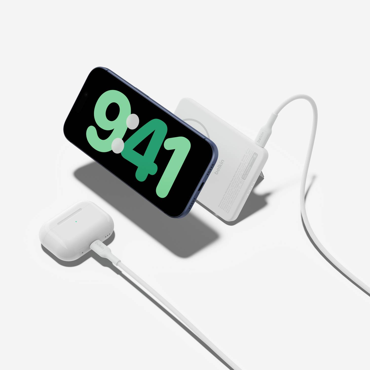 Un smartphone oscuro que muestra las 9:41 junto a un cargador blanco y un estuche de carga blanco.