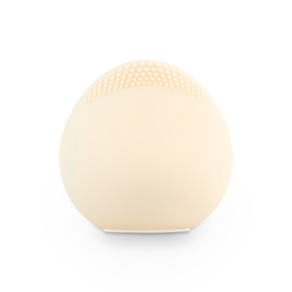 Un dispositivo de limpieza facial color crema, con forma de huevo y pequeñas protuberancias.