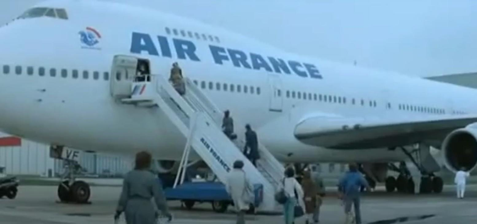 Menschen steigen eine Gangway hinauf und hinunter, ein Flugzeug von Air France steht bereit.