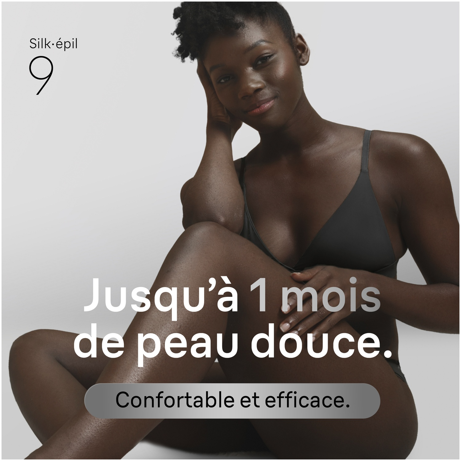 Femme à la peau foncée en lingerie sombre, assise de côté. Texte: Jusqu'à 1 mois de peau douce.