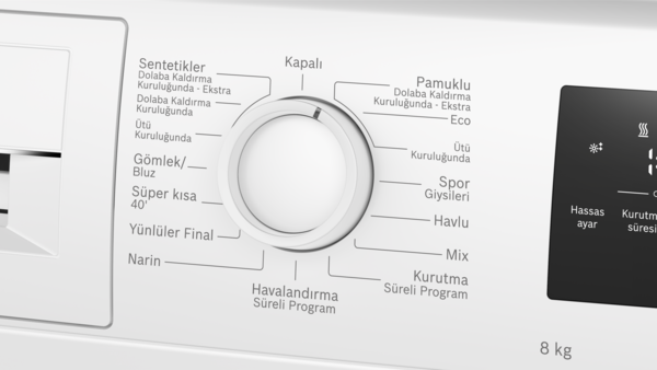 Program seçici kadranlı beyaz çamaşır kurutma makinesi kontrol panelinin yakın çekimi.