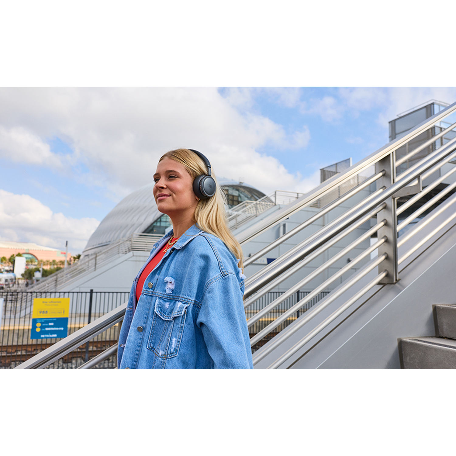 A young woman wearing headphones on an upward-leading staircase.