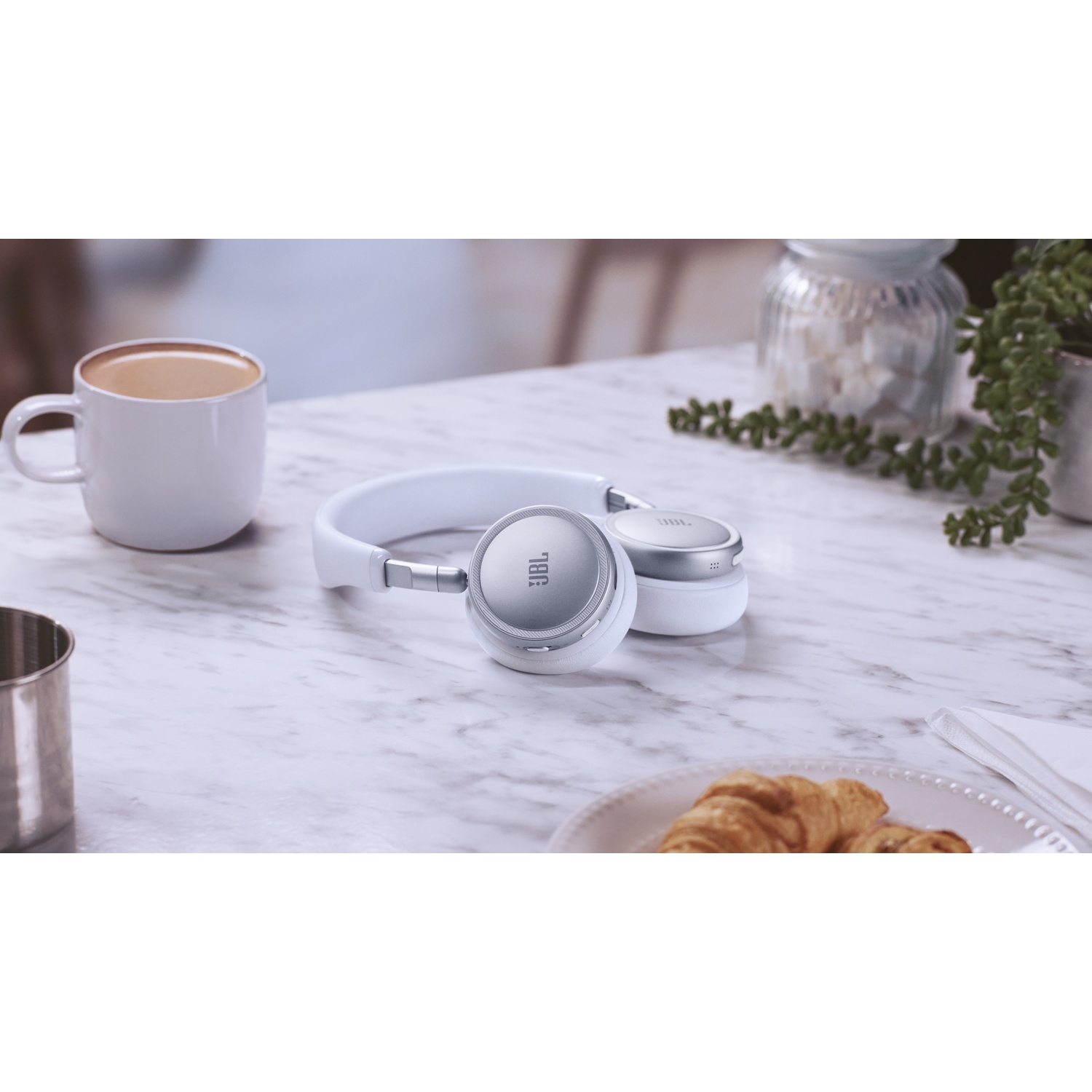 Casque blanc sur table marbre près de tasse café et croissants.