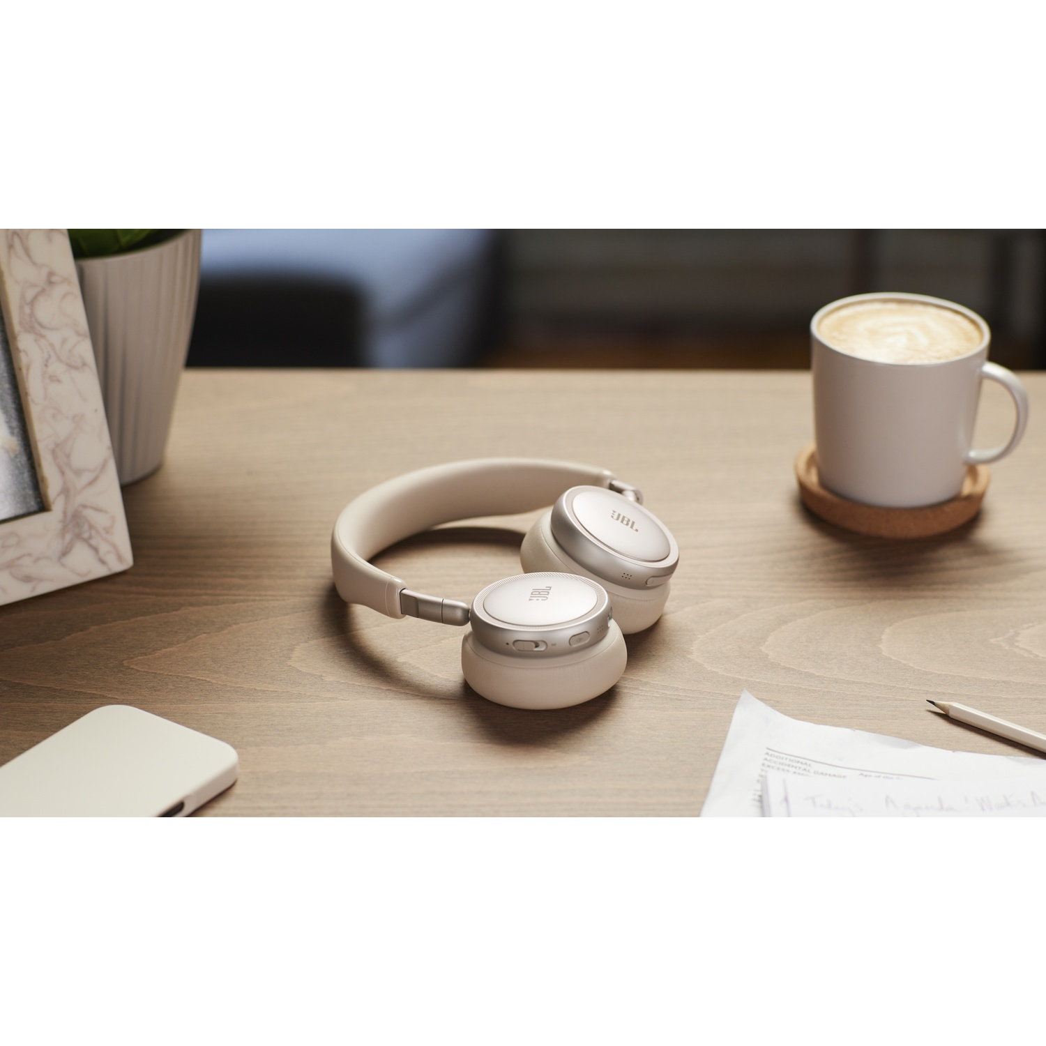 Un casque blanc repose sur un bureau en bois à côté d'une tasse de café.