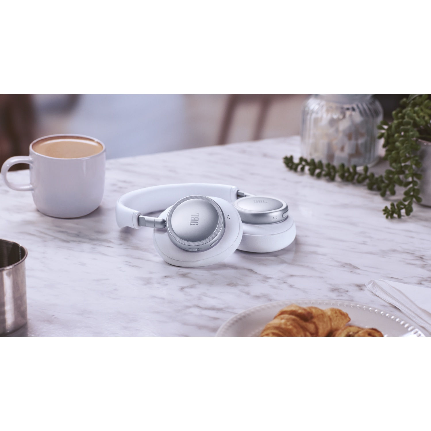 Casque blanc avec tasse de café et croissant sur table en marbre.