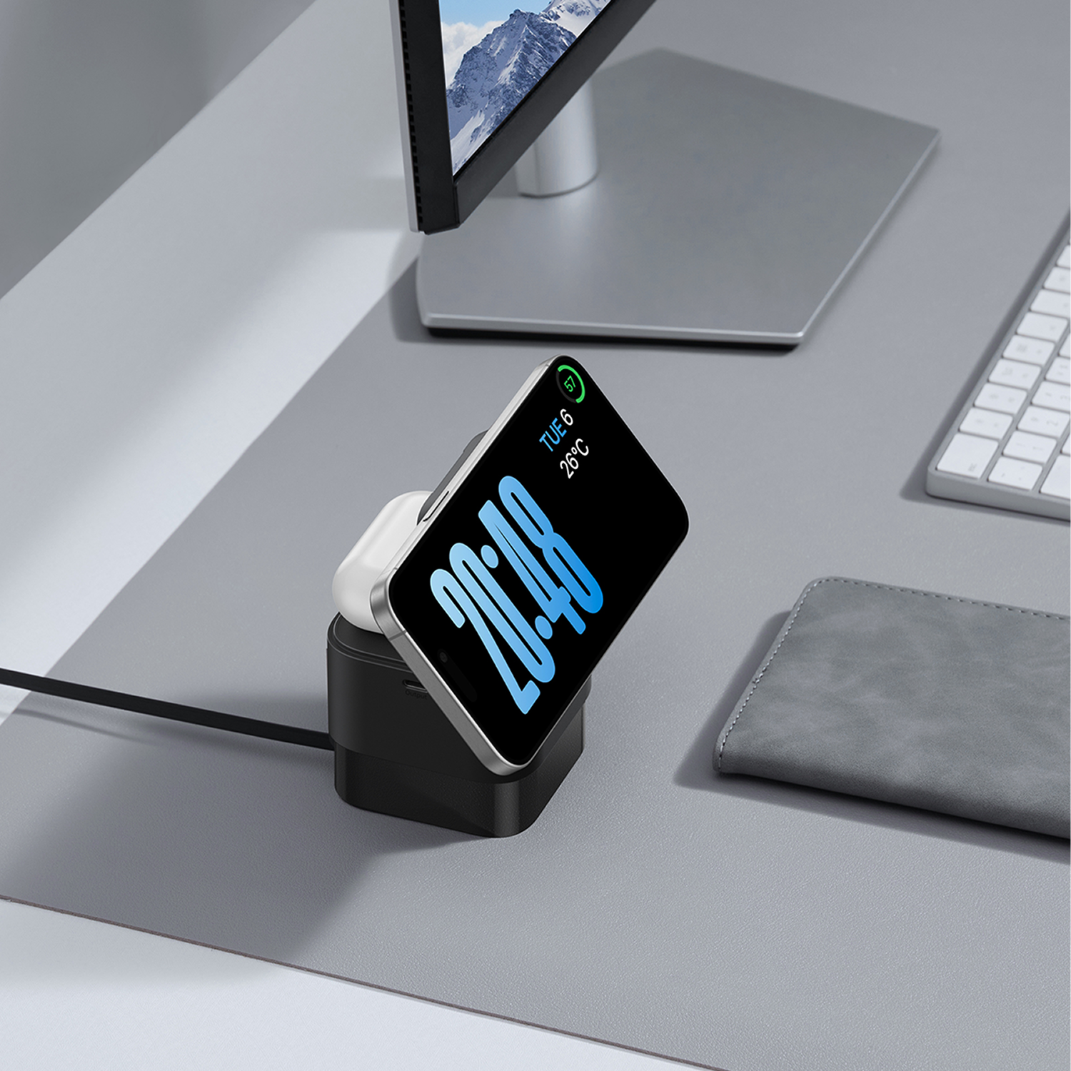 Un soporte de carga negro con un reloj y auriculares en un escritorio.