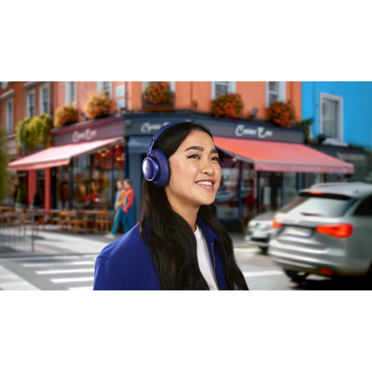 A woman wearing blue headphones smiles, with a city street scene in the background.