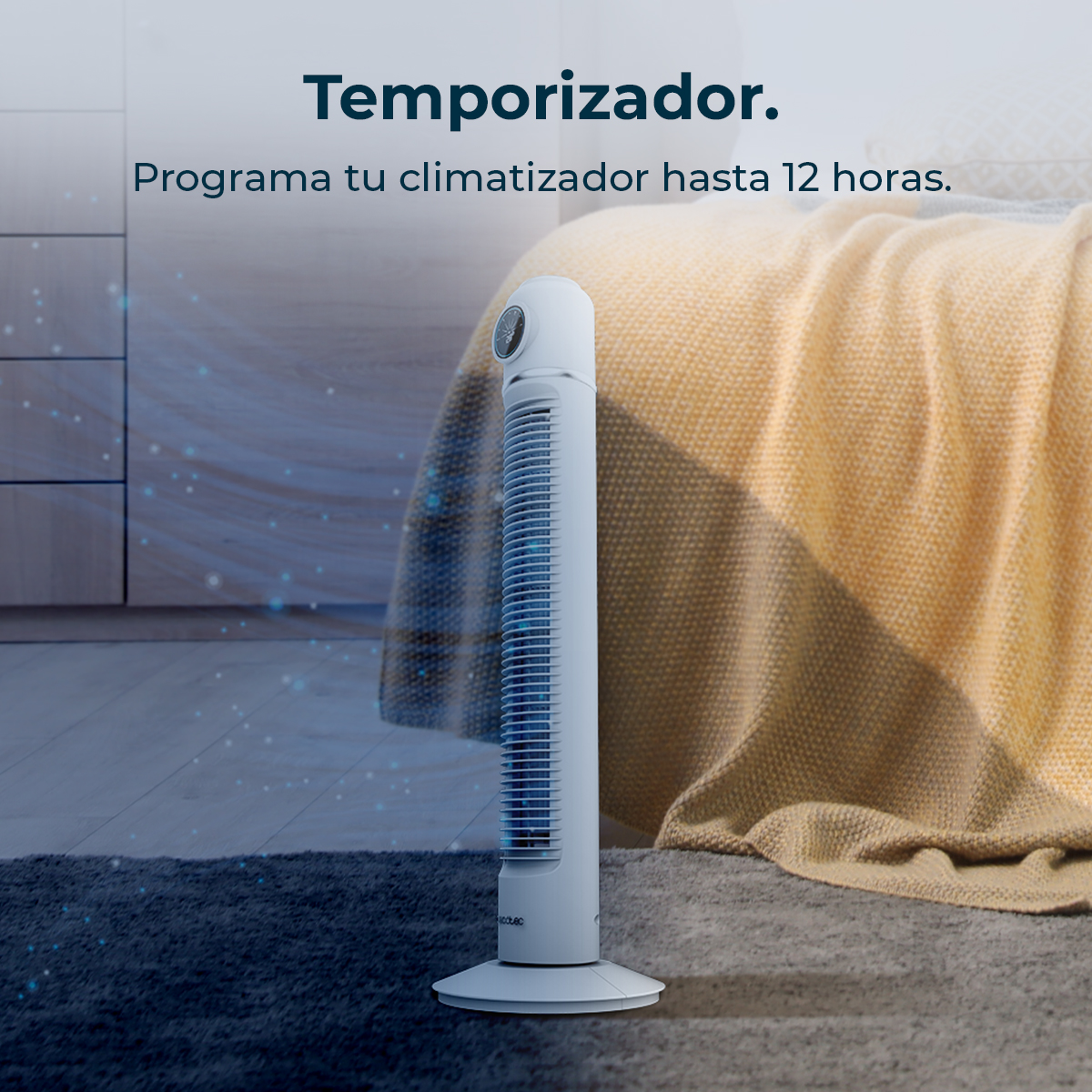 Un ventilador de torre blanco sobre una alfombra frente a una cama con manta amarilla.
