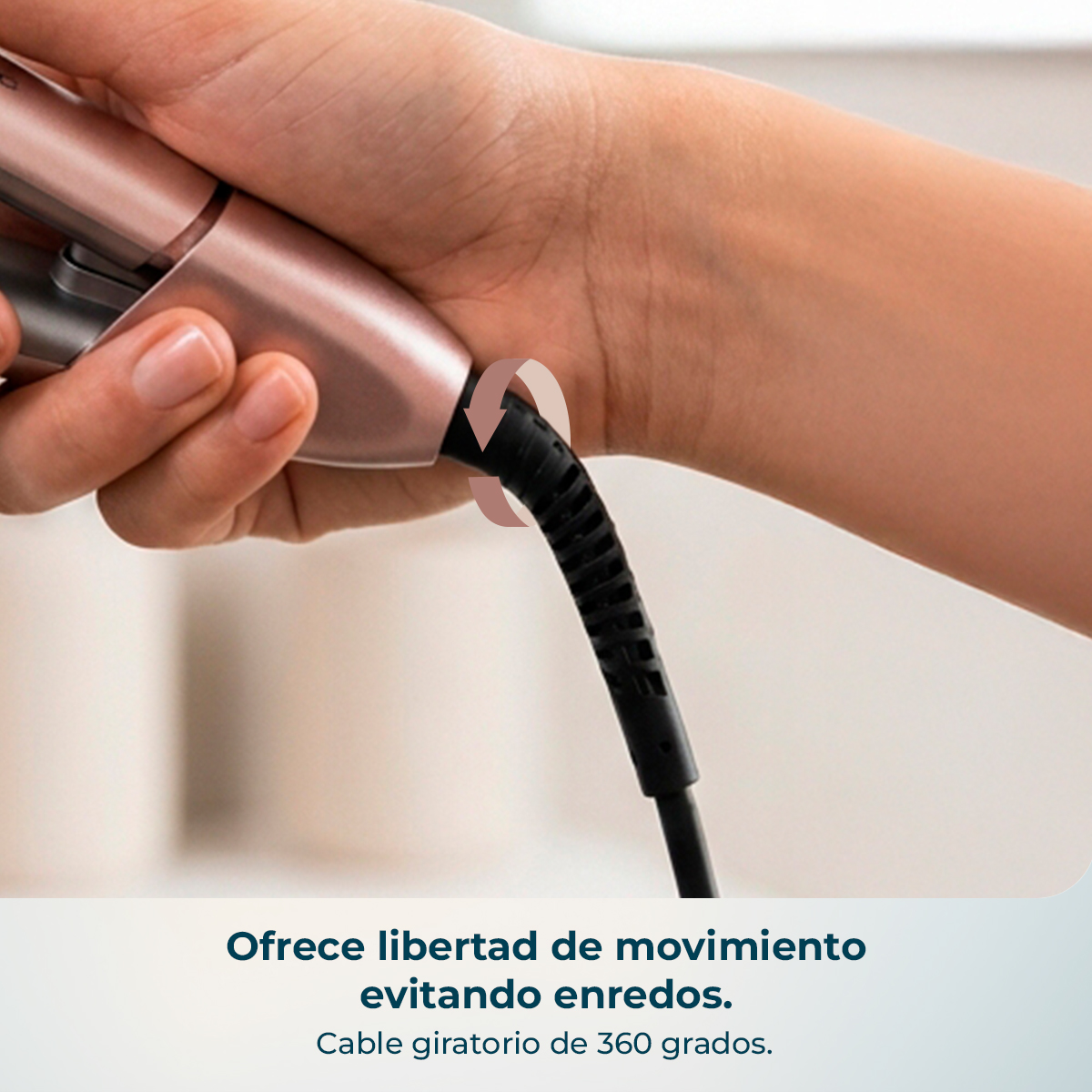 Una mano sostiene una plancha rosa dorada con un cable negro girando alrededor de la muñeca.