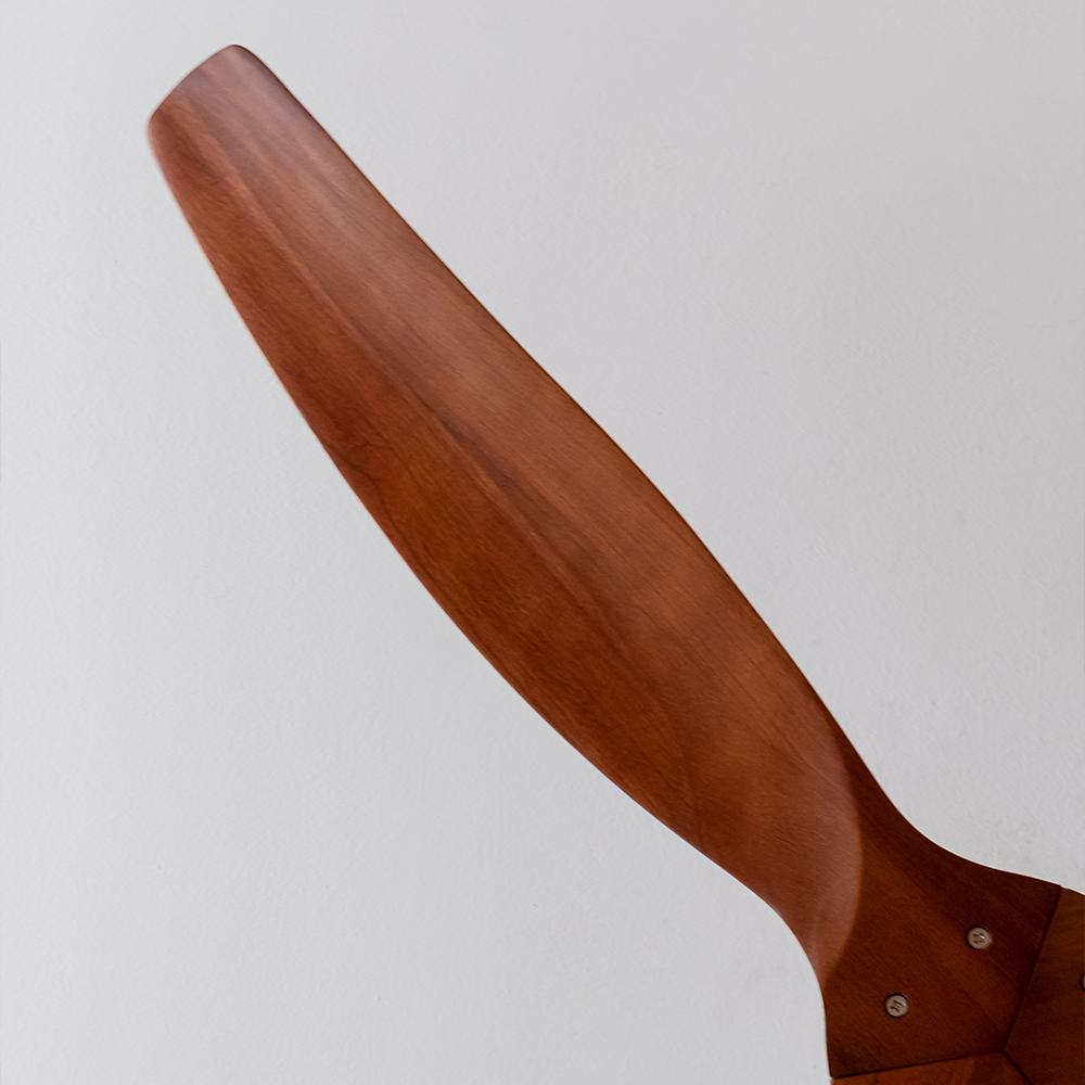 Un hélice de avión de madera con palas marrones sobre fondo blanco.
