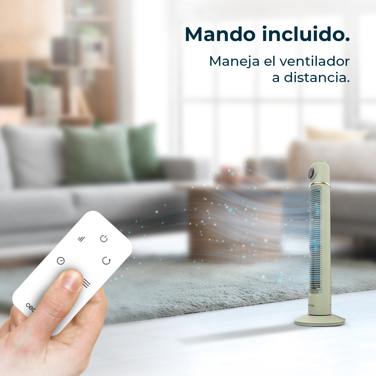 Una mano sostiene un mando a distancia blanco frente a un ventilador de torre.