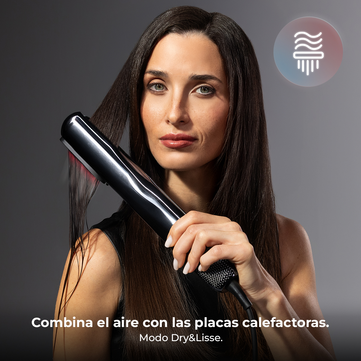 Una mujer peina su pelo oscuro con una plancha negra que emite aire y calor.