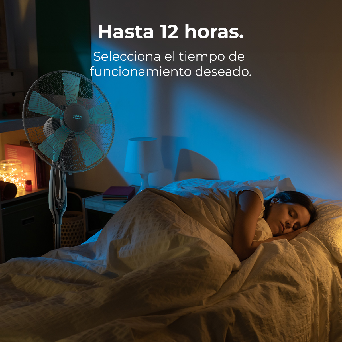 Una mujer duerme en la cama, un ventilador cerca.