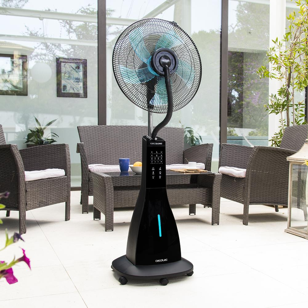 Un ventilador negro con luz azul está en un patio junto a muebles.
