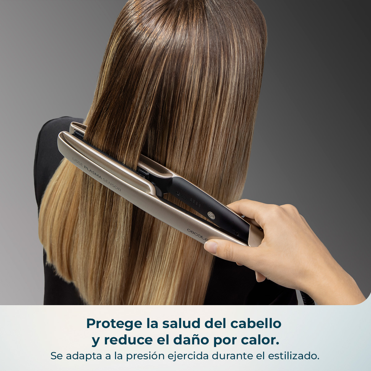 Una mano usa una plancha para el pelo en cabello rubio sobre fondo gris.
