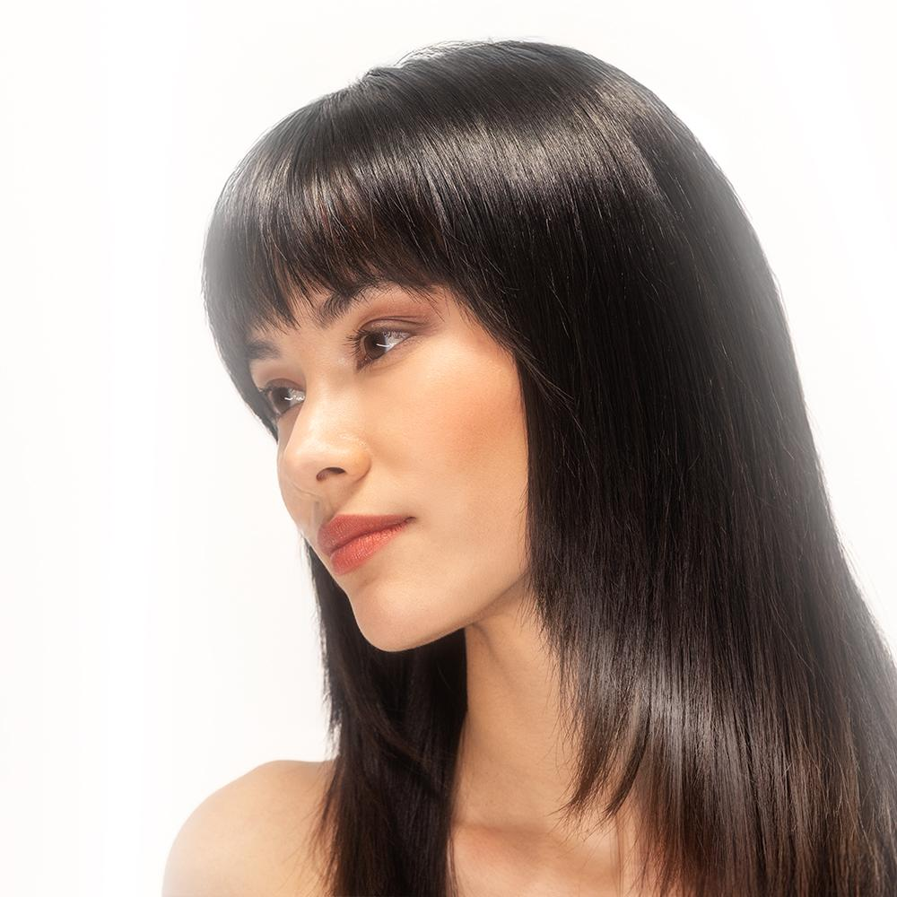 Retrato de una mujer joven con cabello oscuro y flequillo, mirando hacia la izquierda.