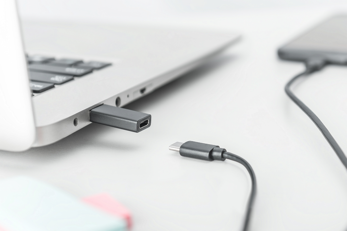 Ein USB-C-Adapter steckt in einem Laptop, daneben liegt ein Kabel.
