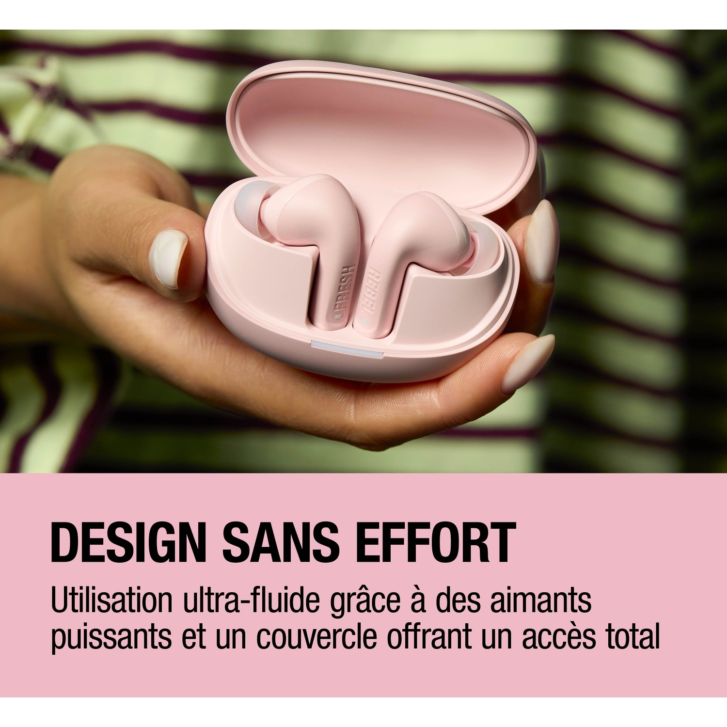 Une main tient un étui de chargement rose avec des écouteurs. Fond rayé.