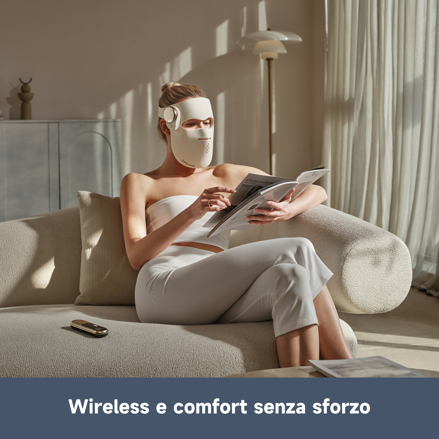 Una donna con maschera facciale legge una rivista seduta su un divano.