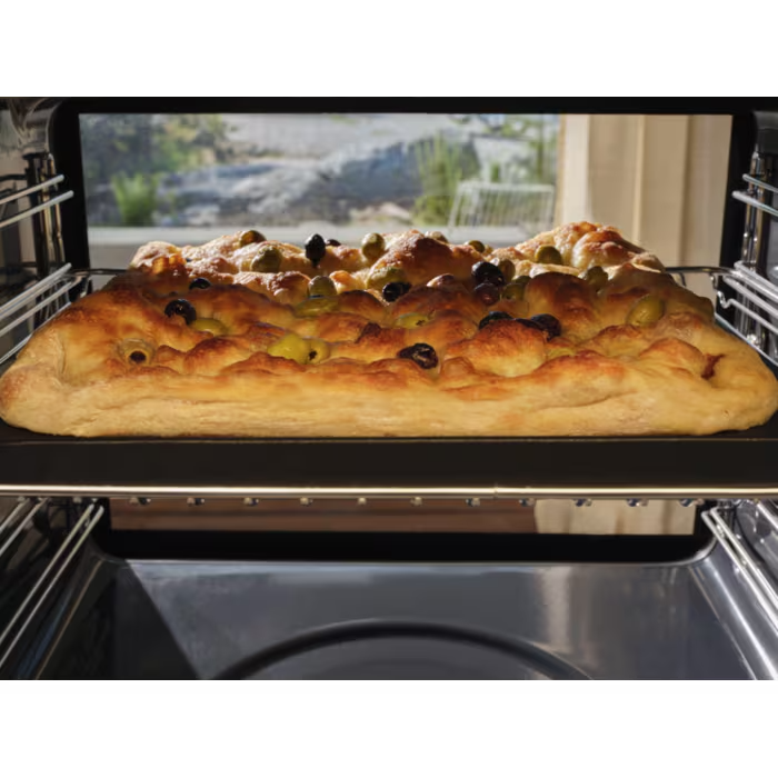 Aranybarna focaccia olajbogyóval sül egy sütőben.