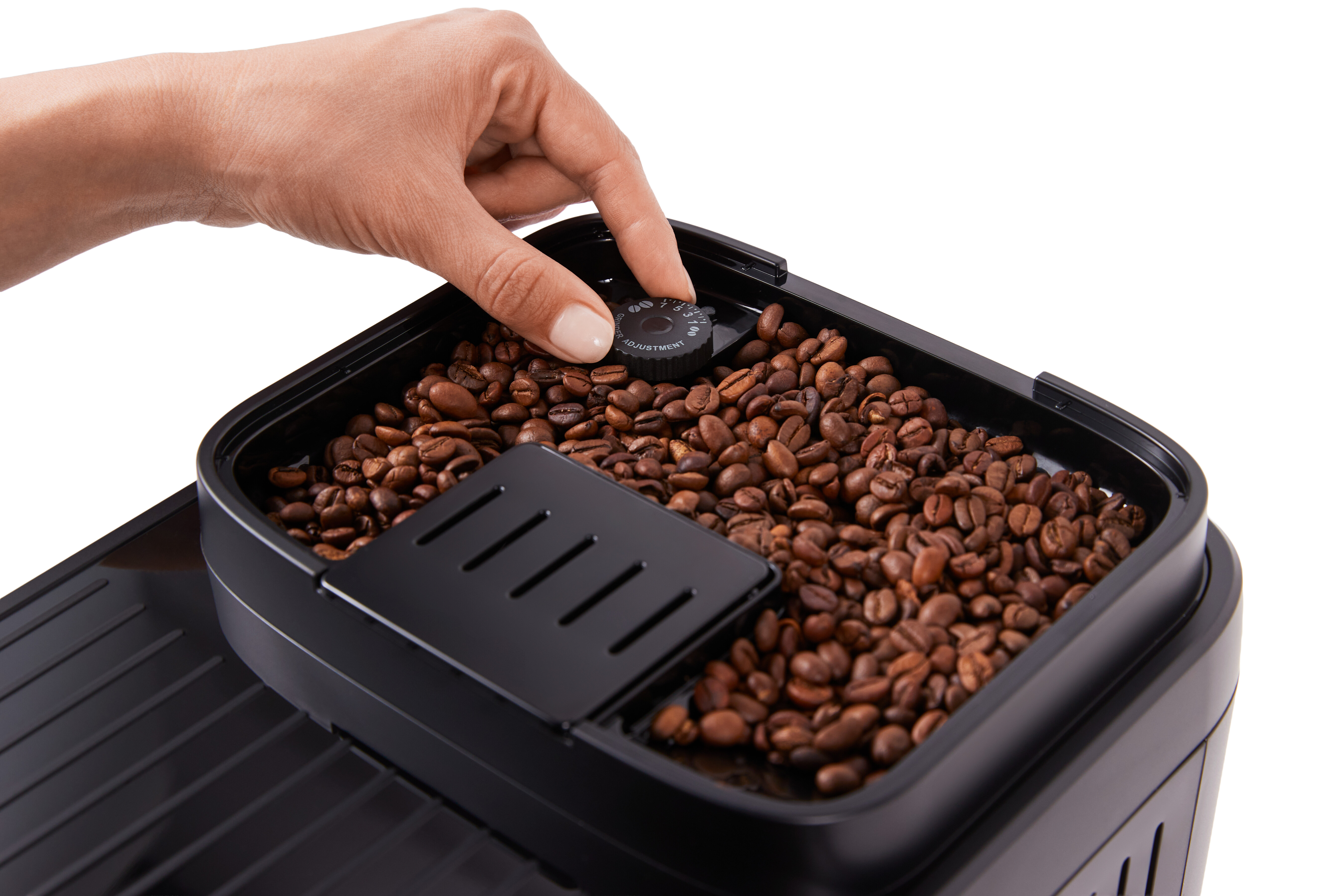 Eine Hand dreht an einem Knopf über Kaffeebohnen in einem Behälter.