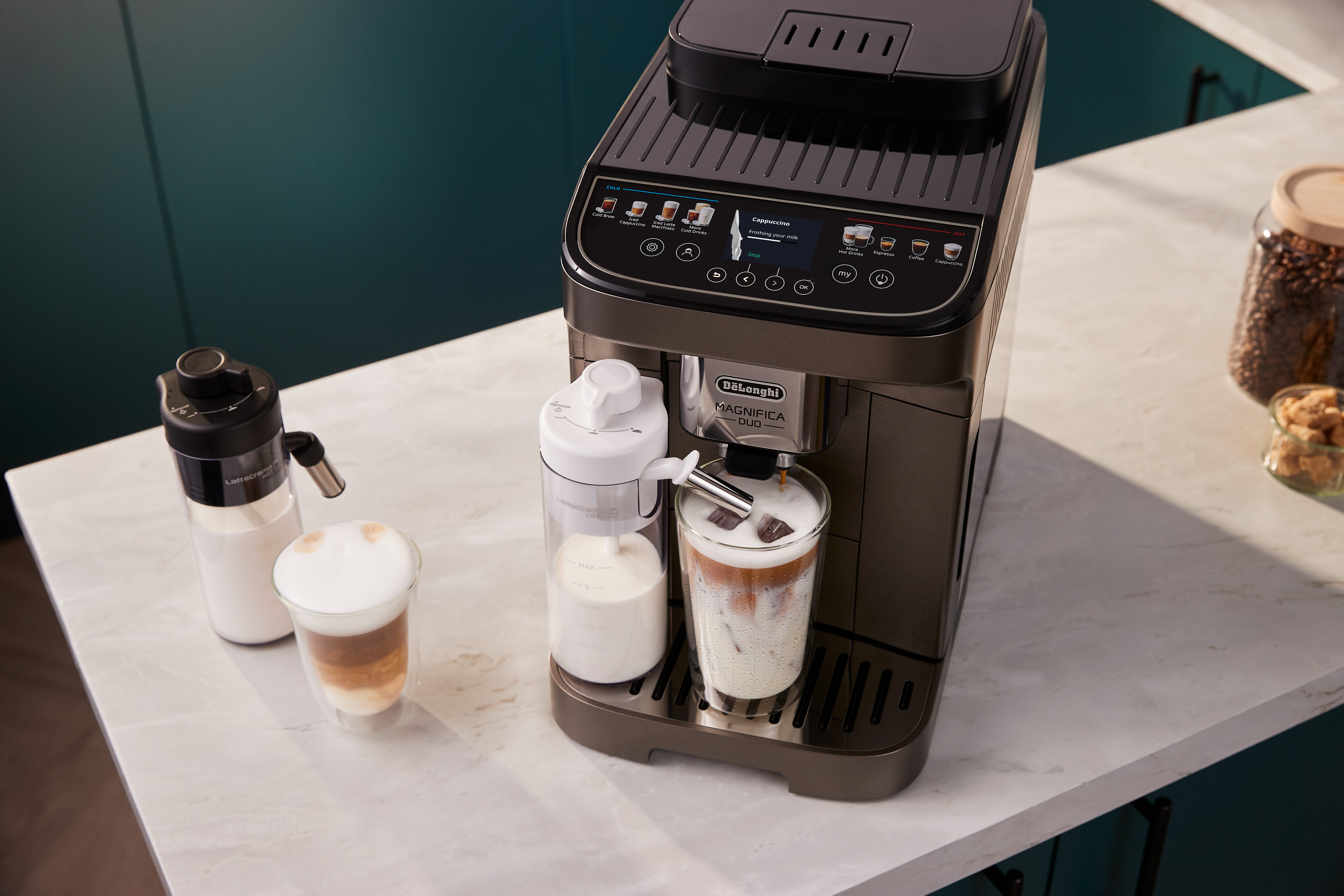 Kaffeemaschine mit Milchkaraffe, zwei fertigen Getränken und Kaffeebohnenglas.