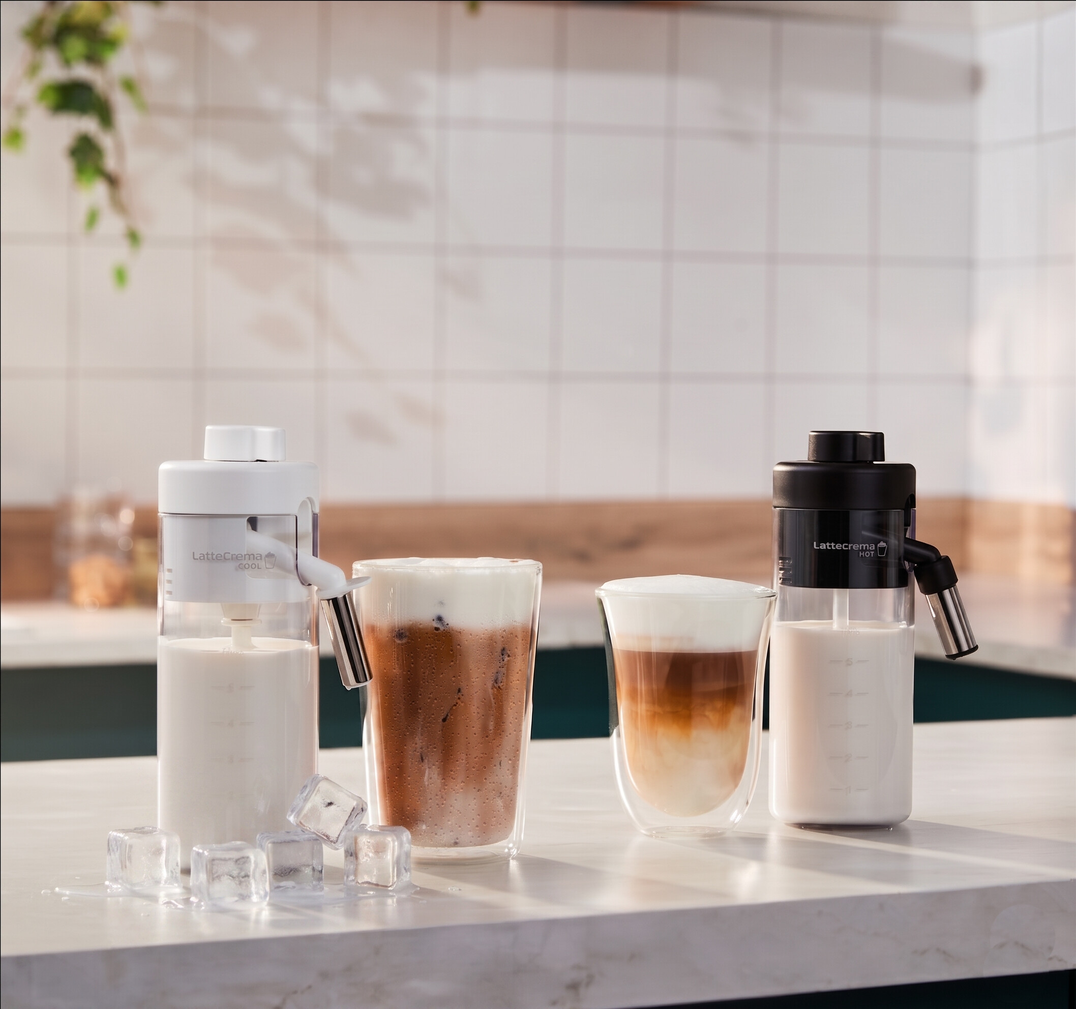 Zwei Milchbehälter, zwei Kaffeegetränke und Eiswürfel auf einer Marmoroberfläche.