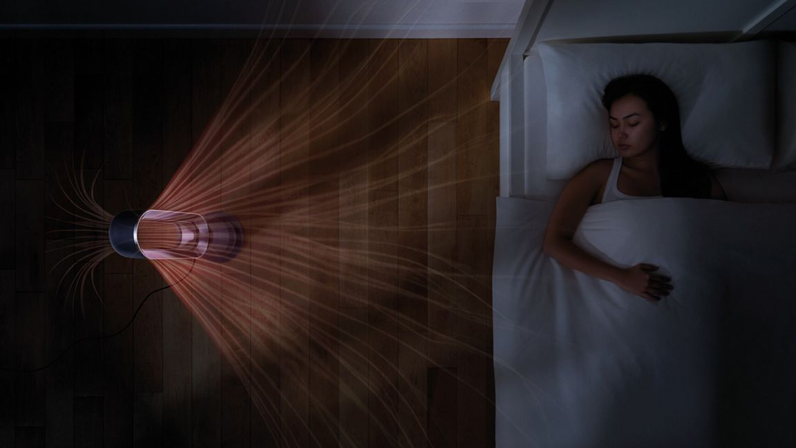 Eine Frau schläft in einem Bett, während ein Lüfter Luft ausstößt.