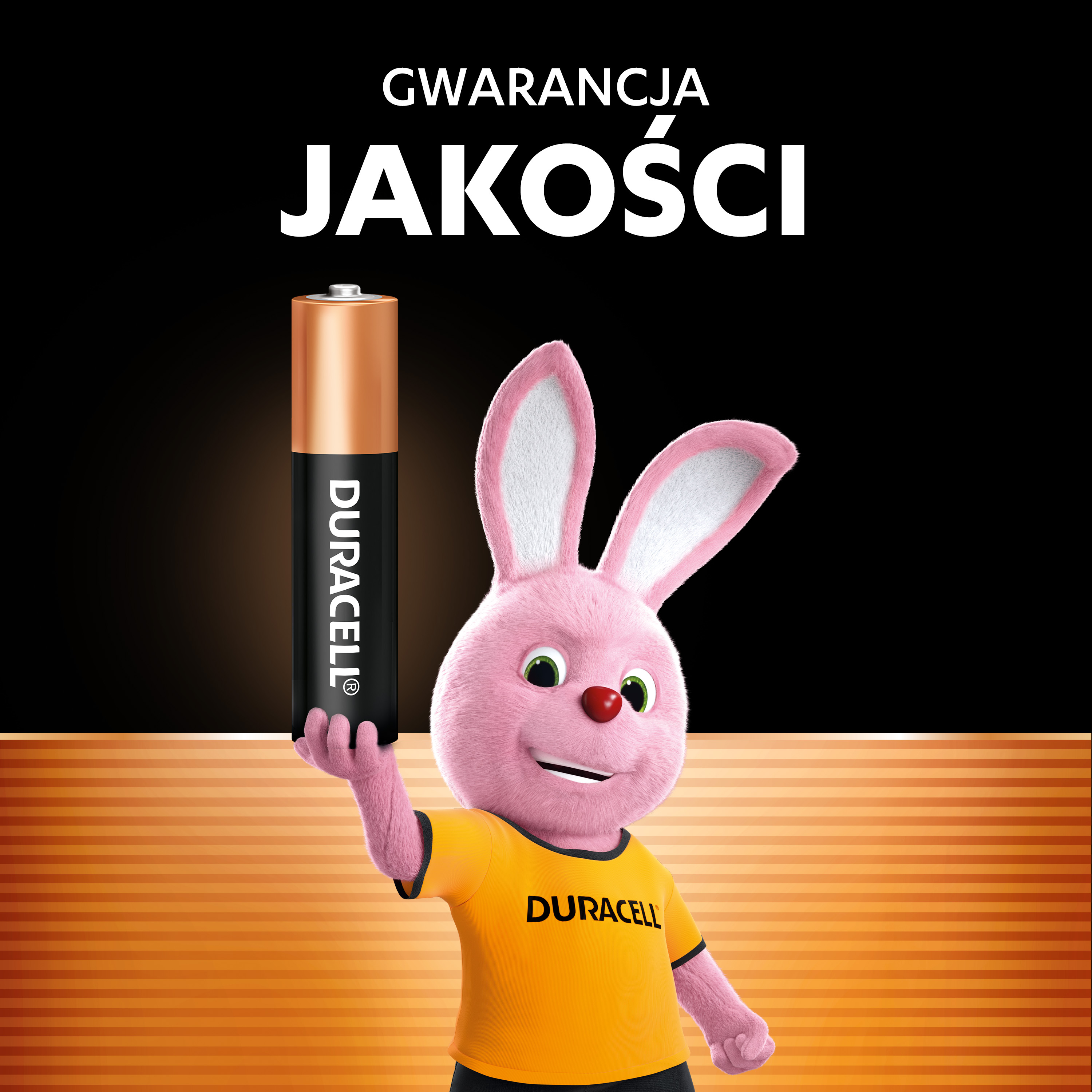 Różowy króliczek trzyma baterię Duracell na czarnym tle z pomarańczowymi paskami.