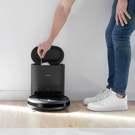 Una persona coloca un paño de limpieza en una estación de carga de robot aspirador.