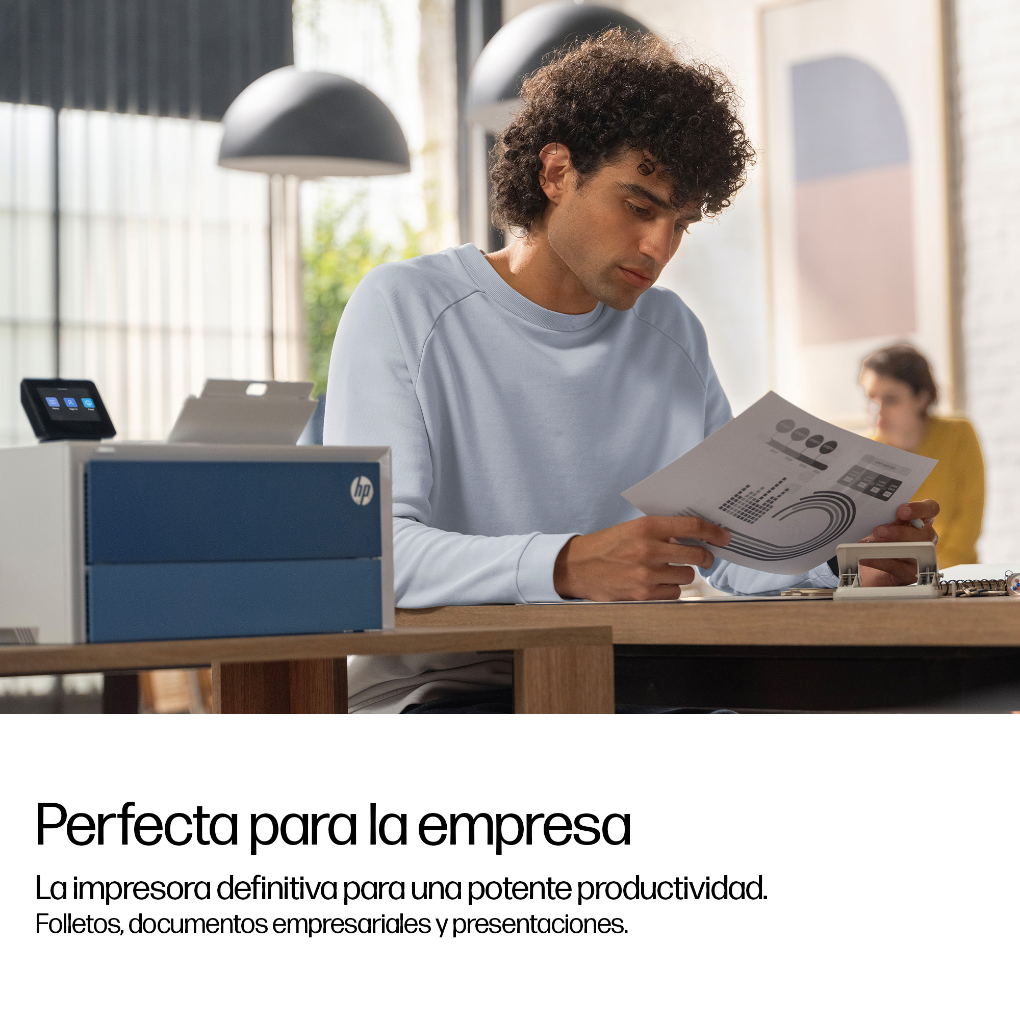 Un hombre revisa documentos junto a una impresora HP.