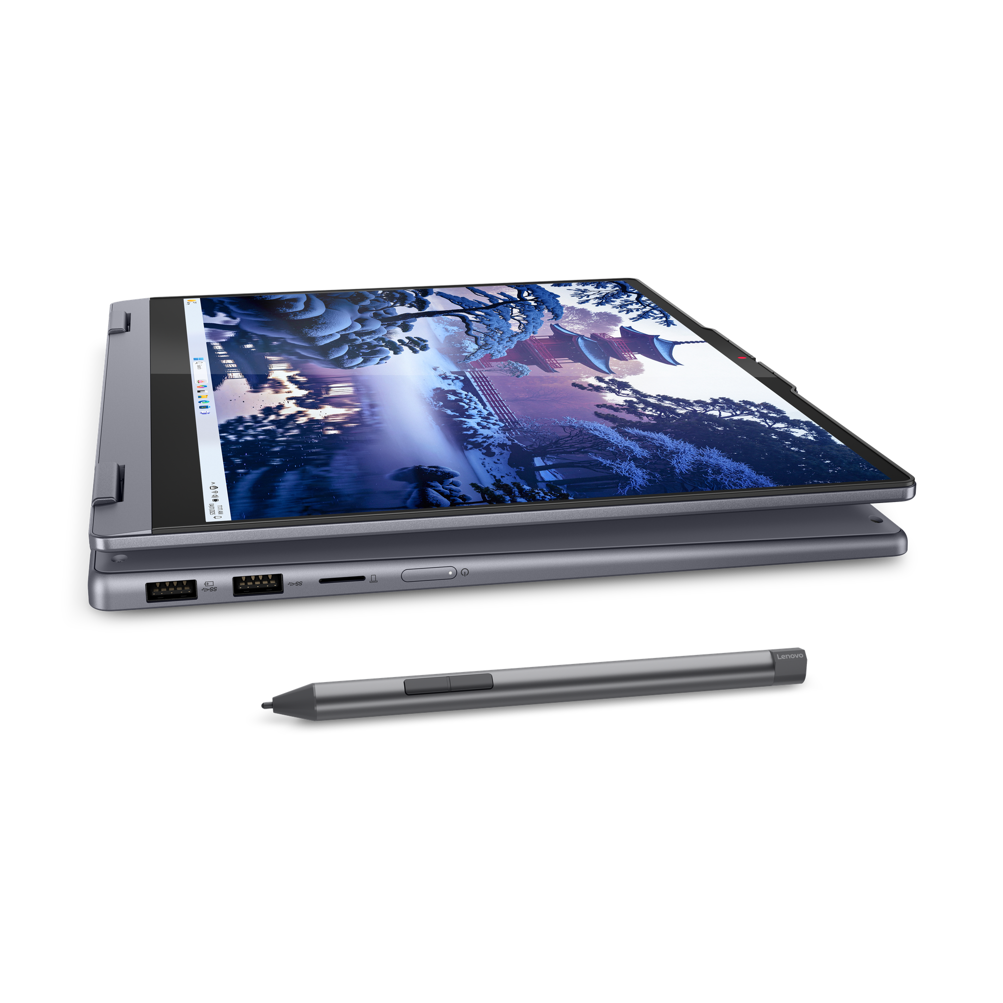 Egy ezüst Lenovo laptop nyitva, téli jelenetet mutat. Egy ceruza előtte fekszik.