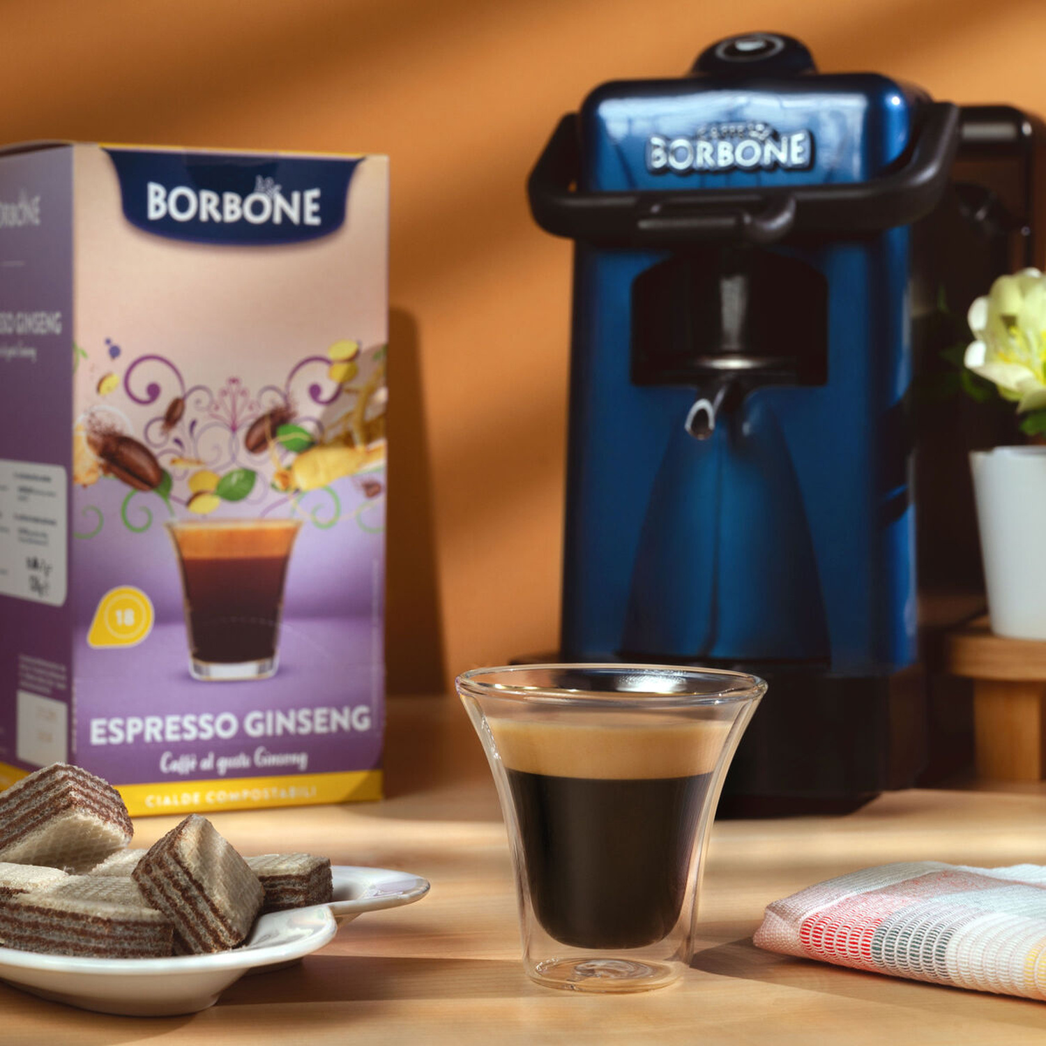 Macchina da caffè Borbone con espresso, biscotti e scatola di caffè al ginseng.